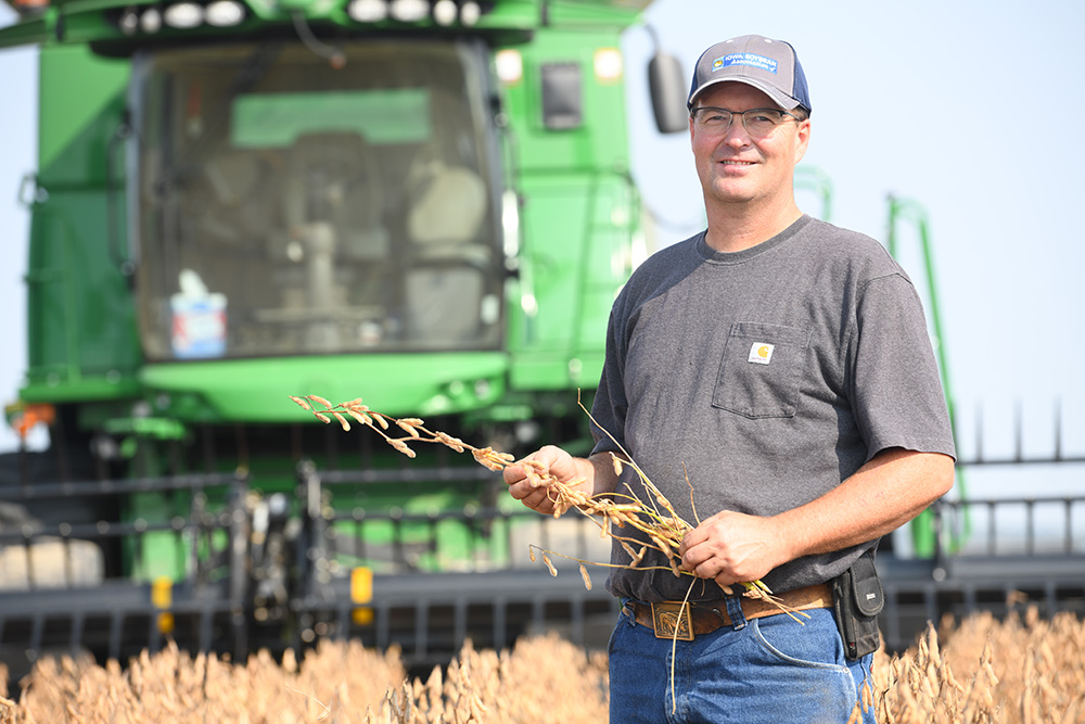 Jeff stands in a soybean field in front of his combine.