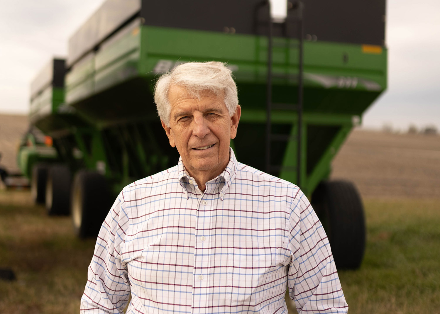 Farmer standing near grain wagons in field