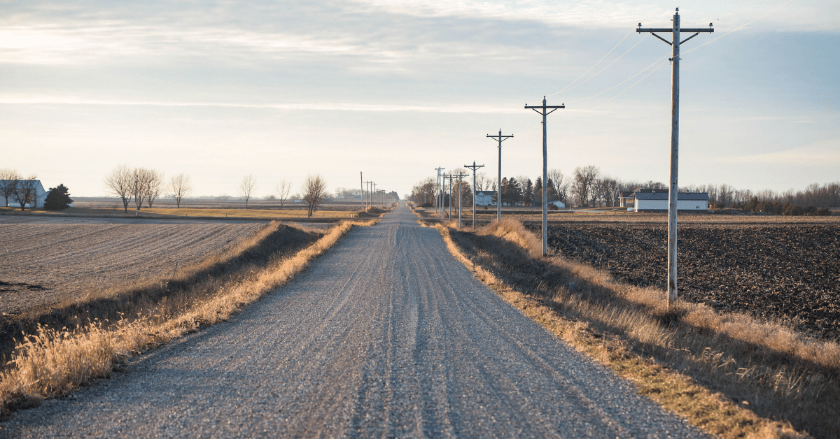 A gravel country road winds past a farmstead.