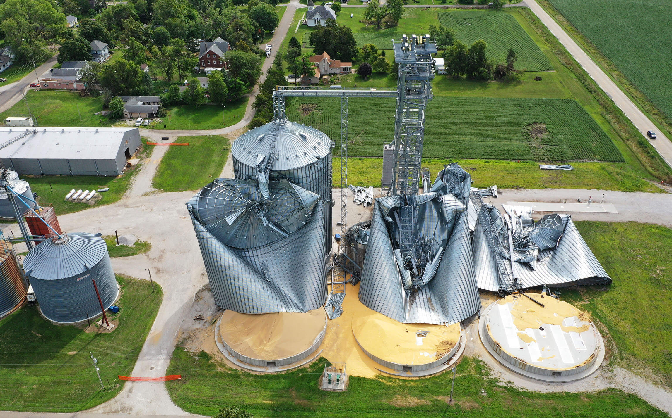 Smashed grain bins with leftover corn on ground lay fal