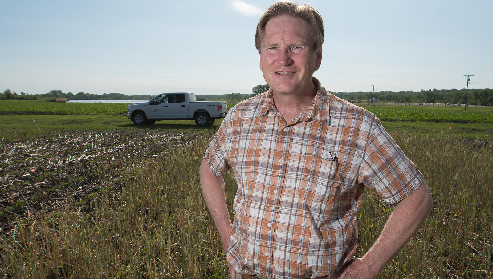 Scott Nelson poses in front of farm field with pickup i