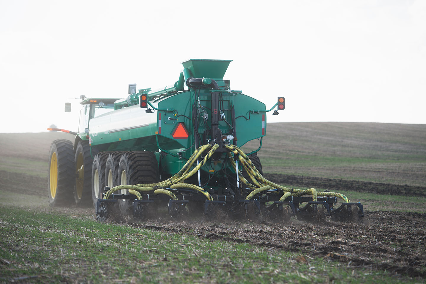 A farmer operates a manure spreader in one of their fie