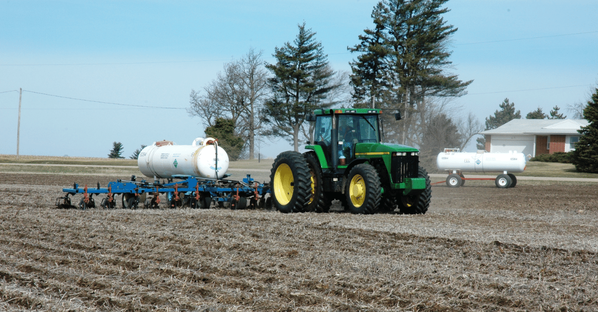 A tractor pulls an implement across a soybean field.