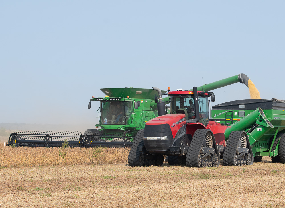 A combine unloads soybeans into a grain cart during soy