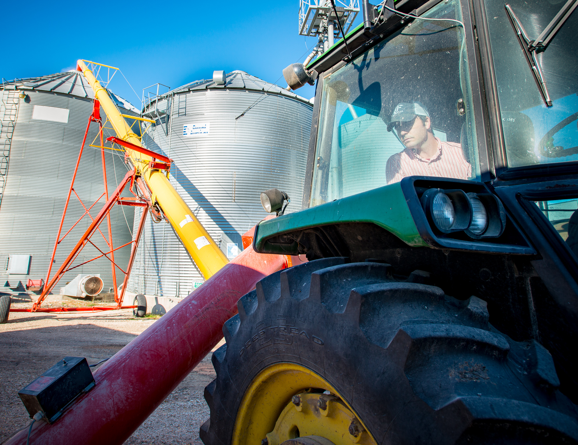 AJ Blair drives his tractor past two grain bins