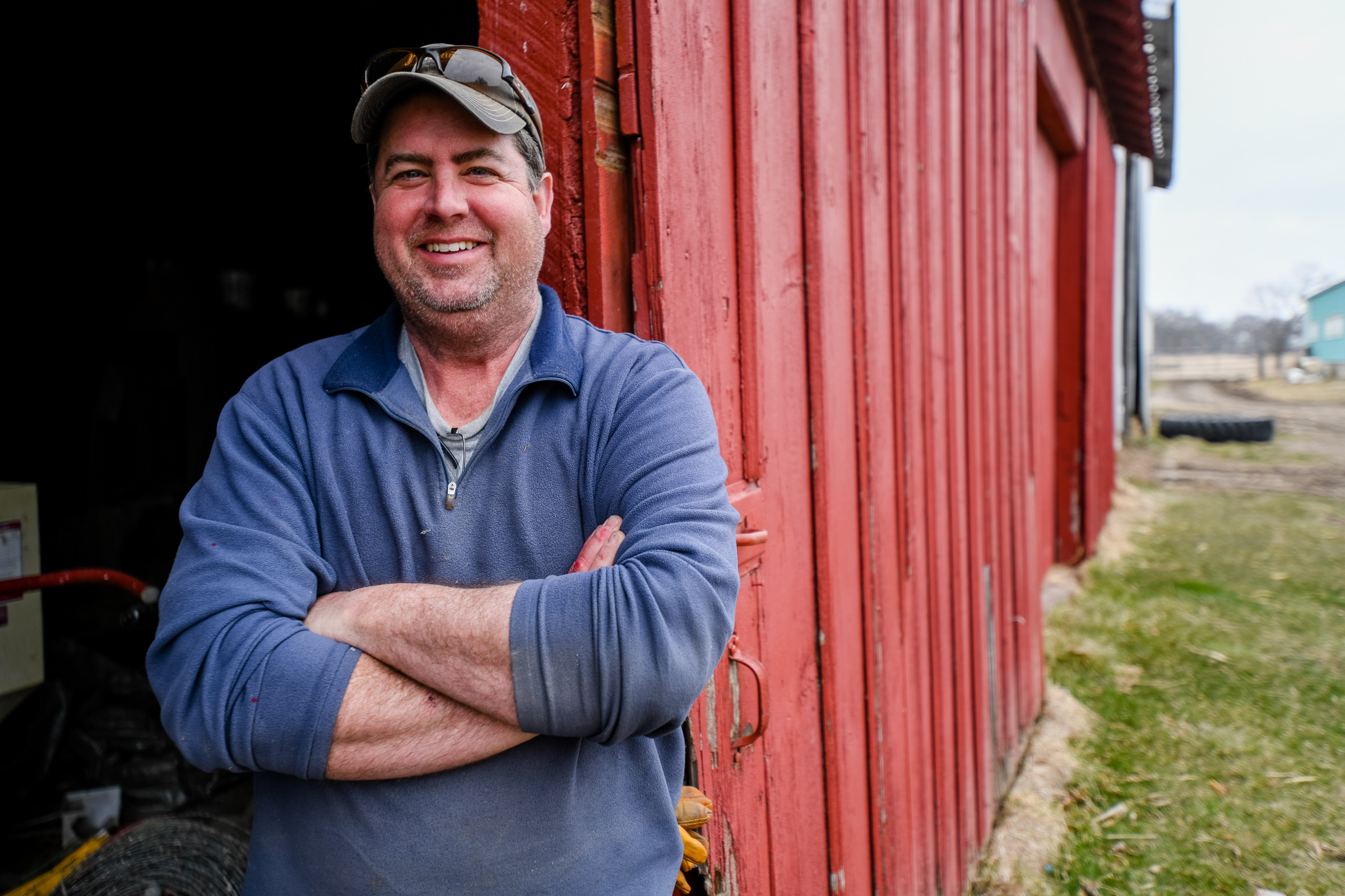 Man smiling in front of red barn
