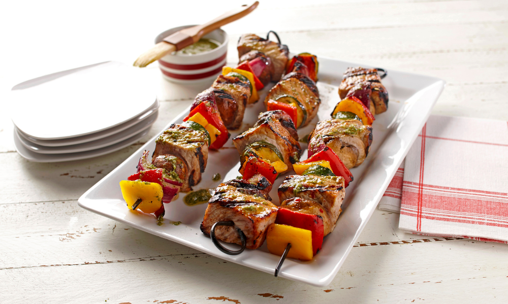 Pork and veggie kabobs sit on a plate ready to eat