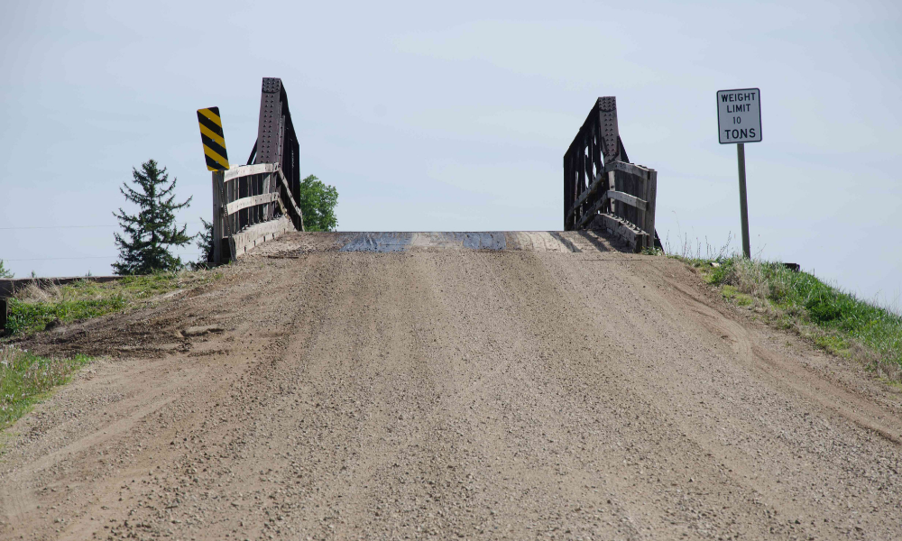 A gravel road leads to a bridge with a 10 ton weight li