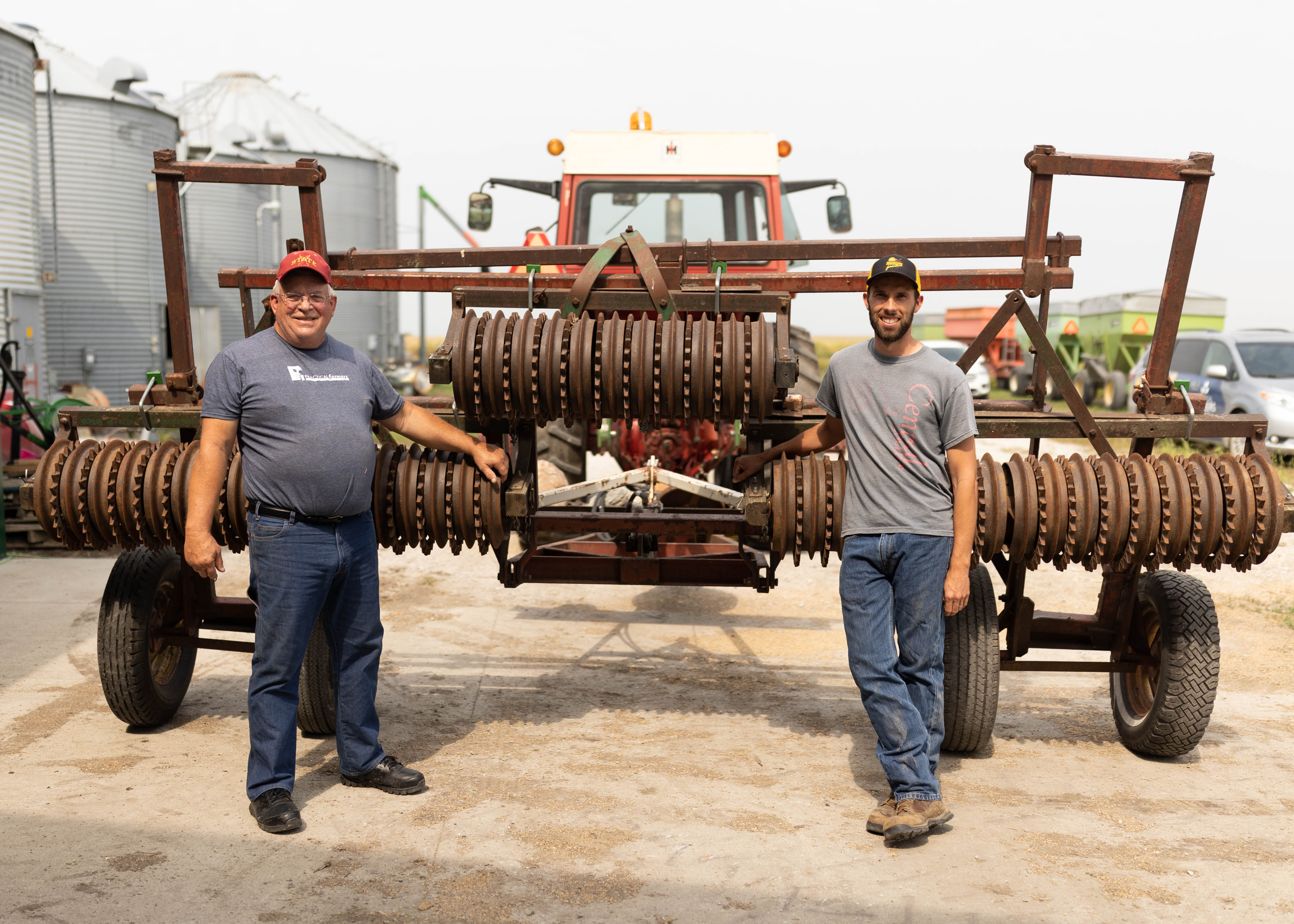 two men standing near a cultipacker