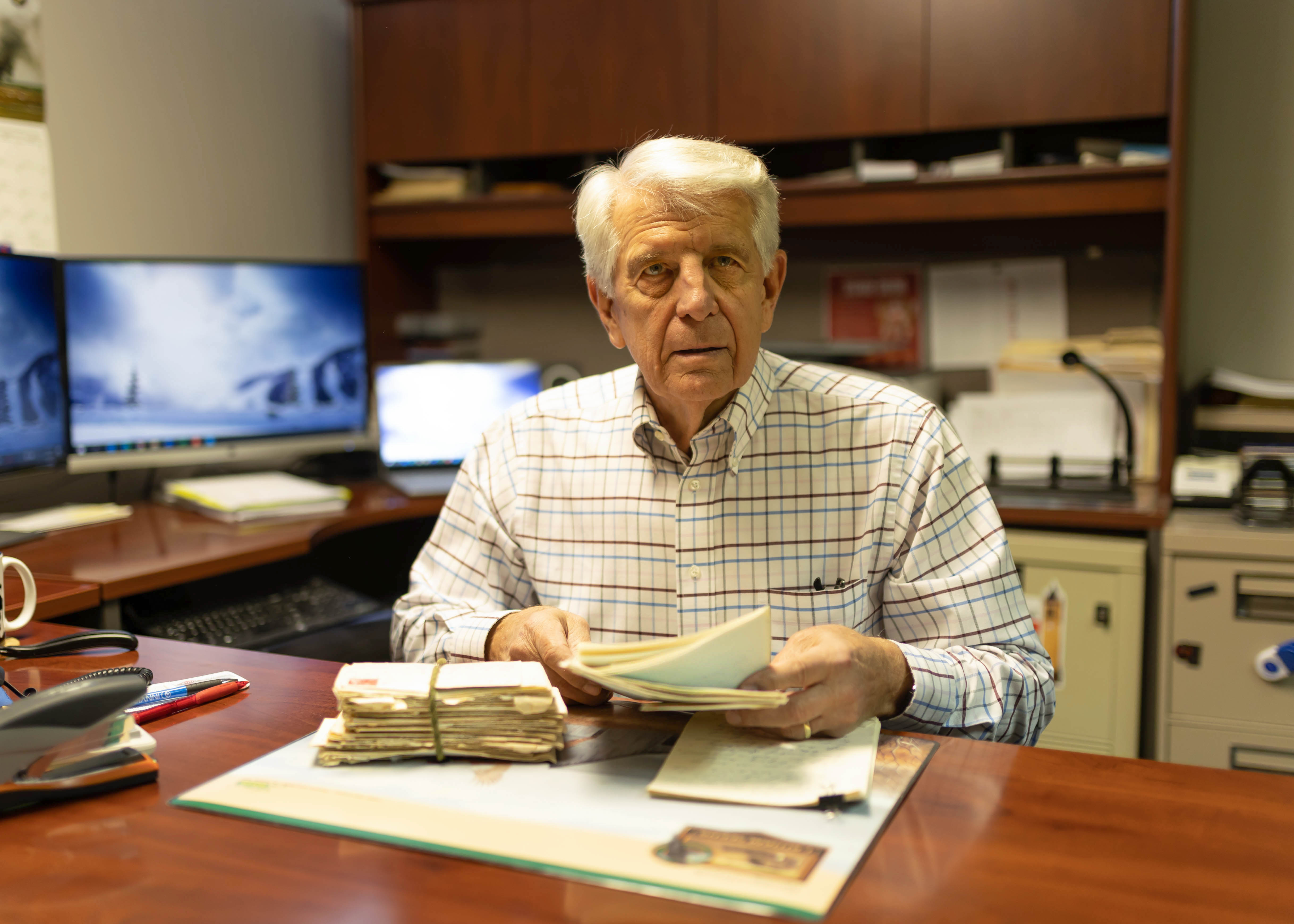 Vietnam veteran sits at his desk with a stack of letter
