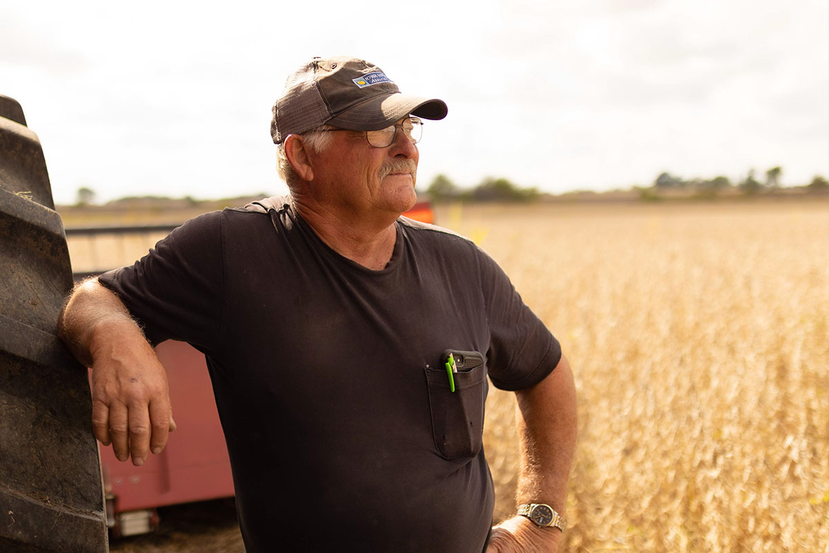 Farmer standing next to combine in field