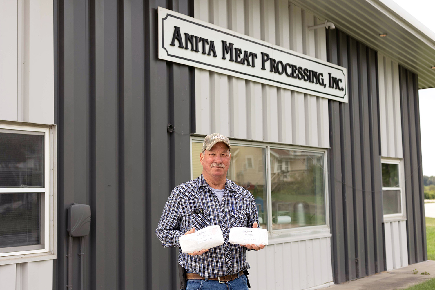 Iowa farmer standing in front of meat processing buildi
