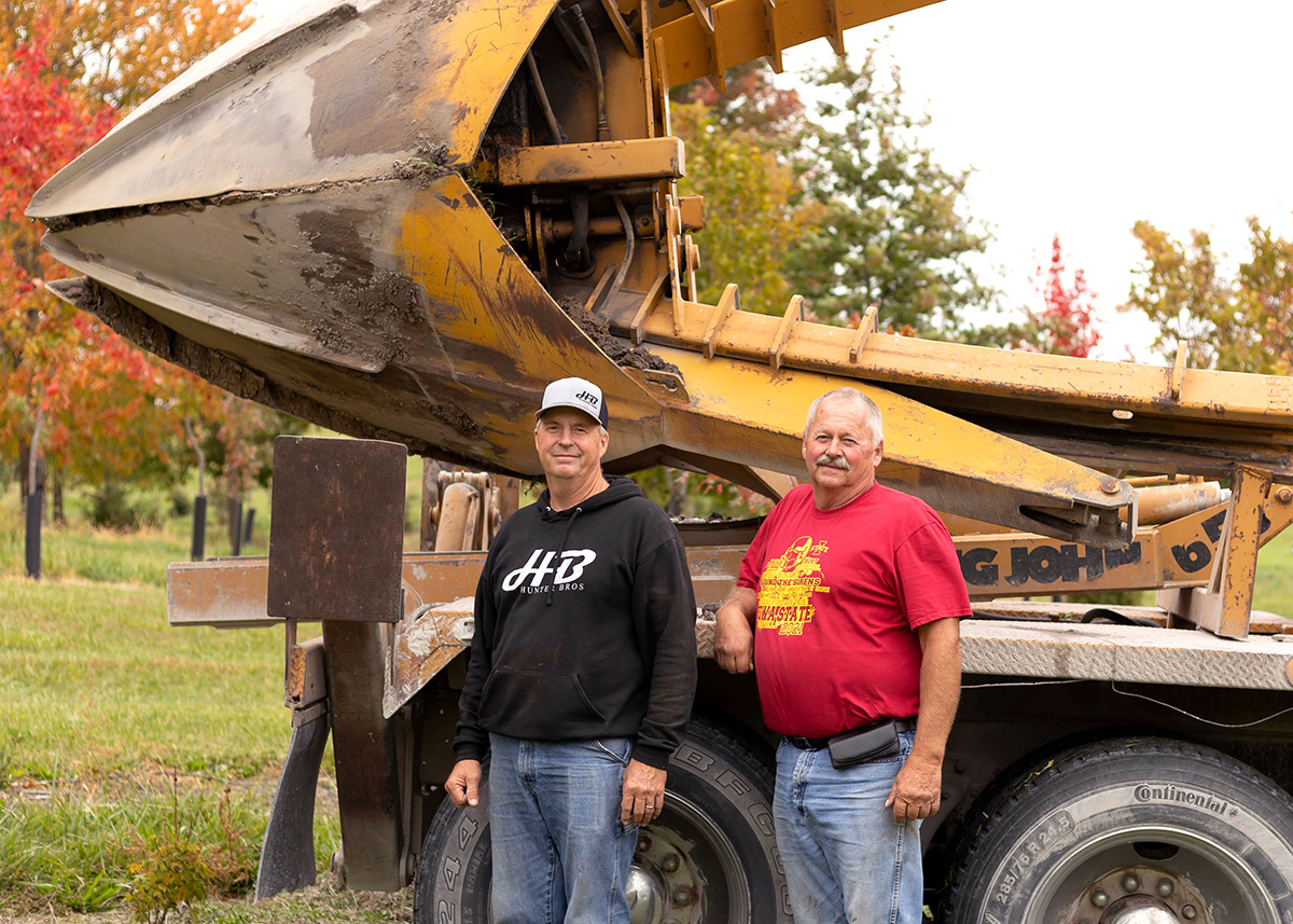 Hunter brothers in front of tree farm machinery