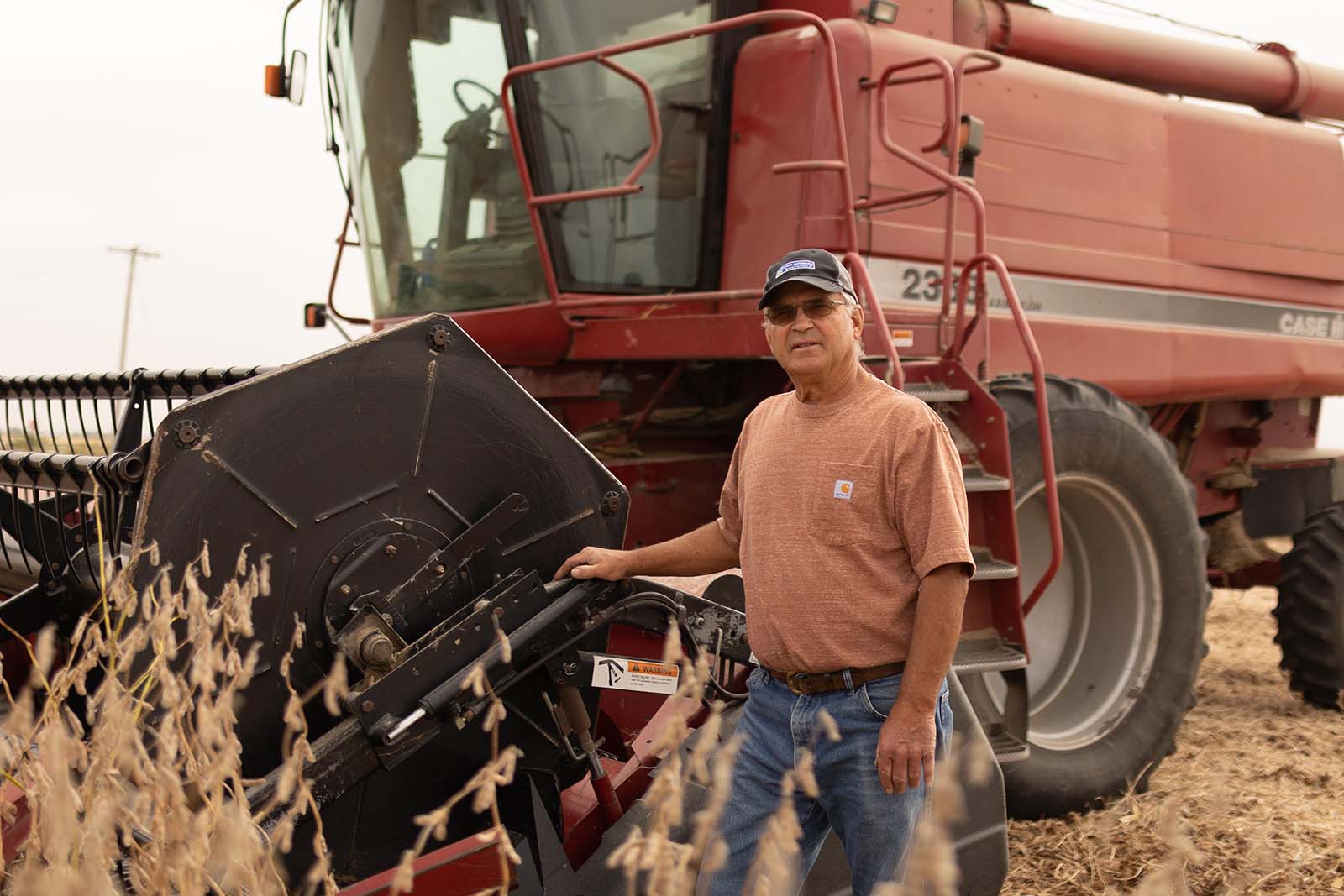 Iowa soybean farmer standing near combine