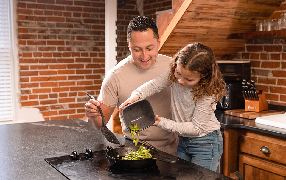 Father and daughter cooking in kitchen