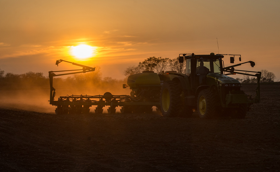 John Deere tractor in field with planter.