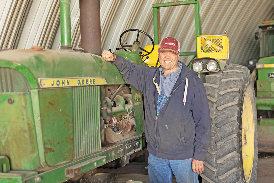 Farmer standing next to John Deere Tractor