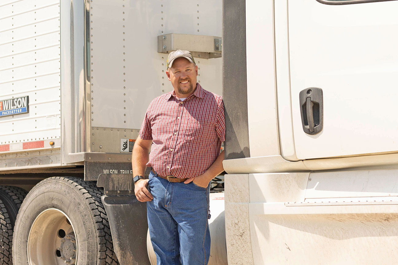 Farmer standing next to tractor and trailer