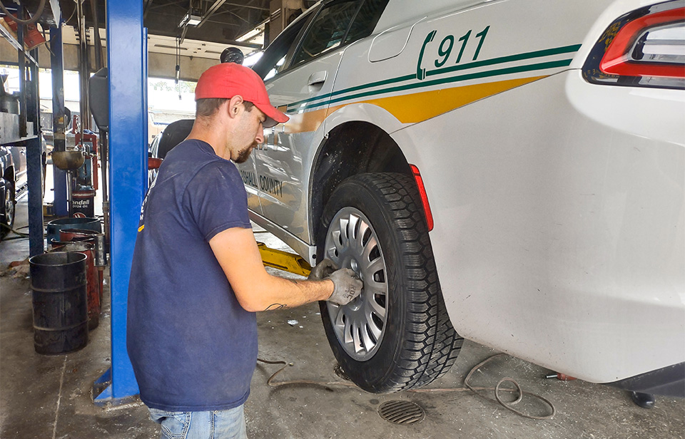 Auto shop workers installing tires on sheriff cruiser