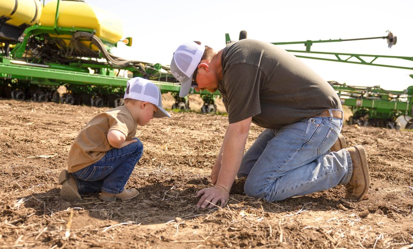 Farmer and son checking soybeans after planting