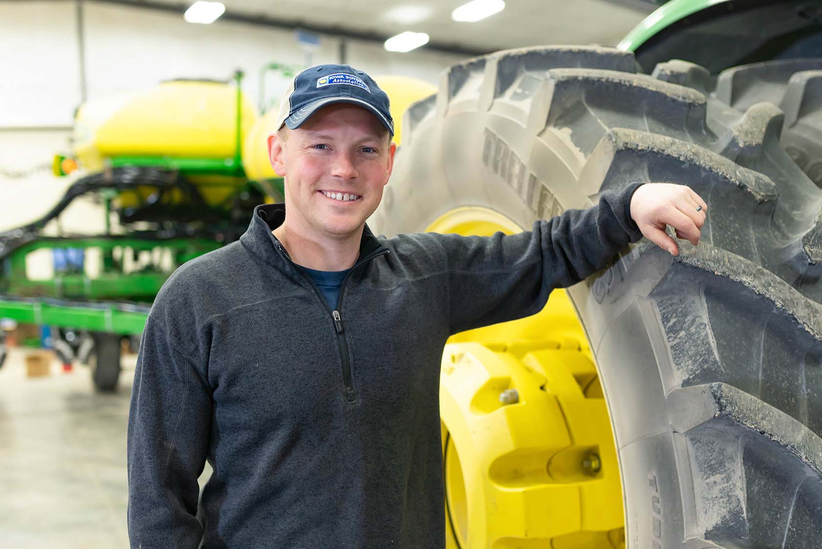 Farmer leaning against tractor tire in machine shed