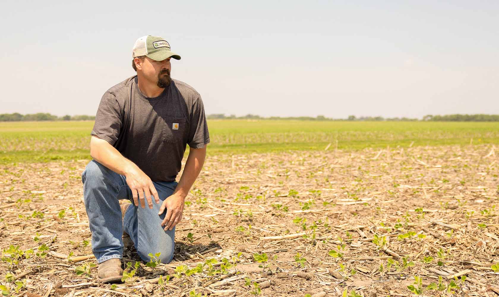 Farmer kneeling down in field