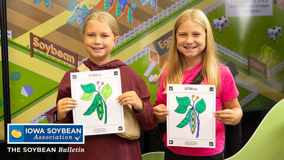 Girls holding up their coloring sheets at the Iowa Stat