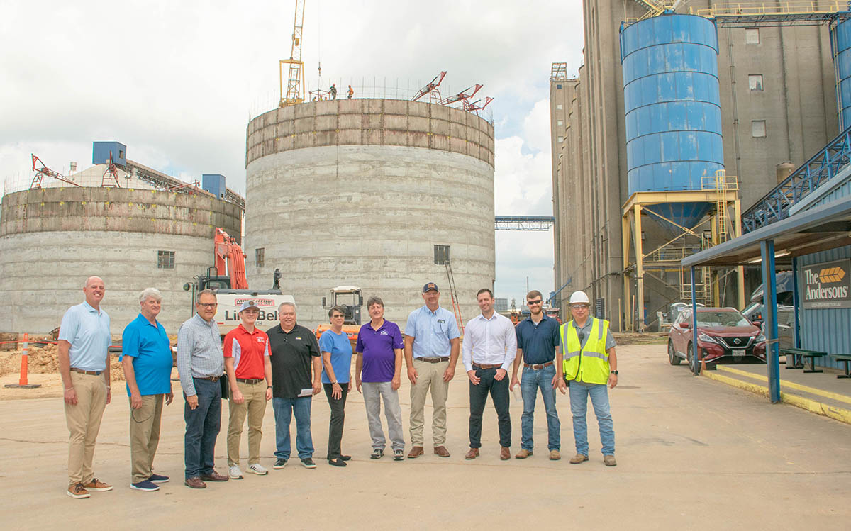 Farmers standing at large grain storage facility
