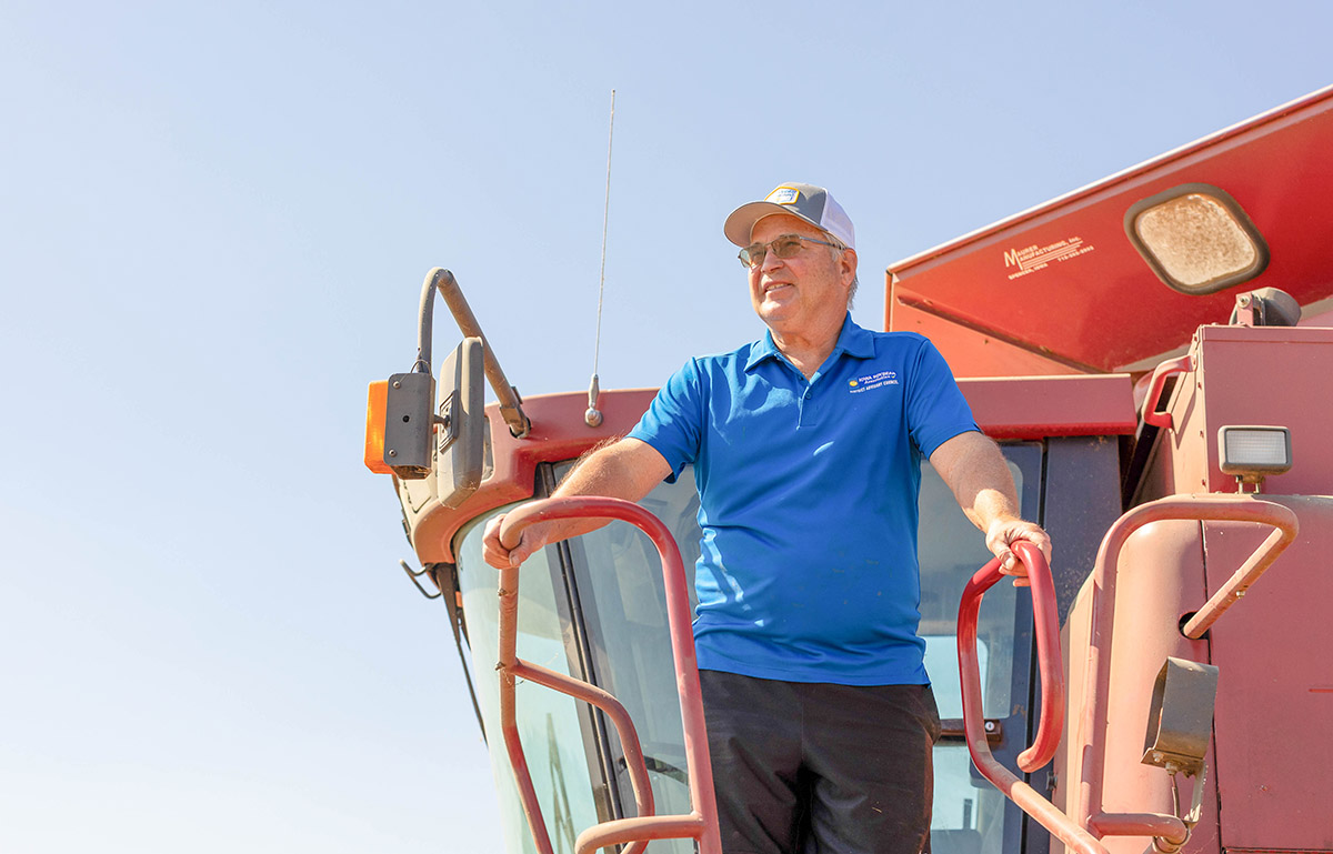 Farmer standing on combine looking across soybean field