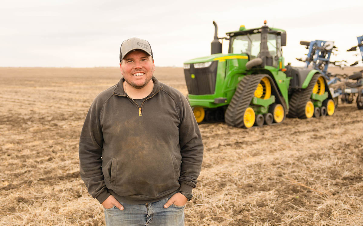 Farmer standing in field next to tractor