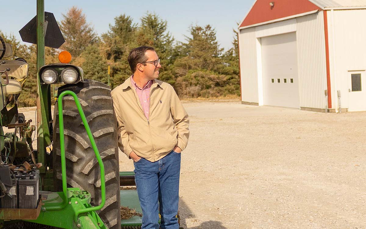Skyler Rinker Farmer leaning next to tractor