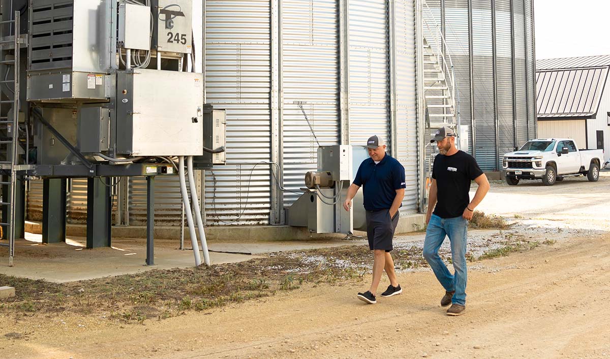 Farmer and AGI rep walking past grain bins