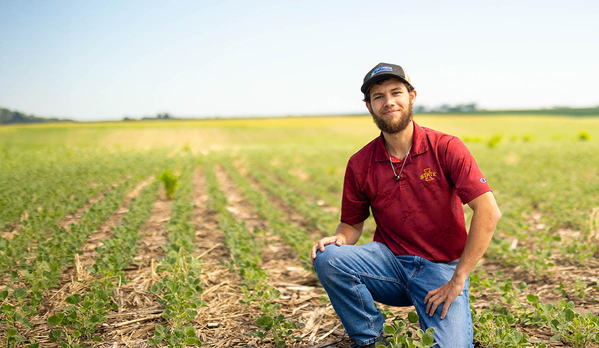 Conservation agronomist kneeling down in soybean field