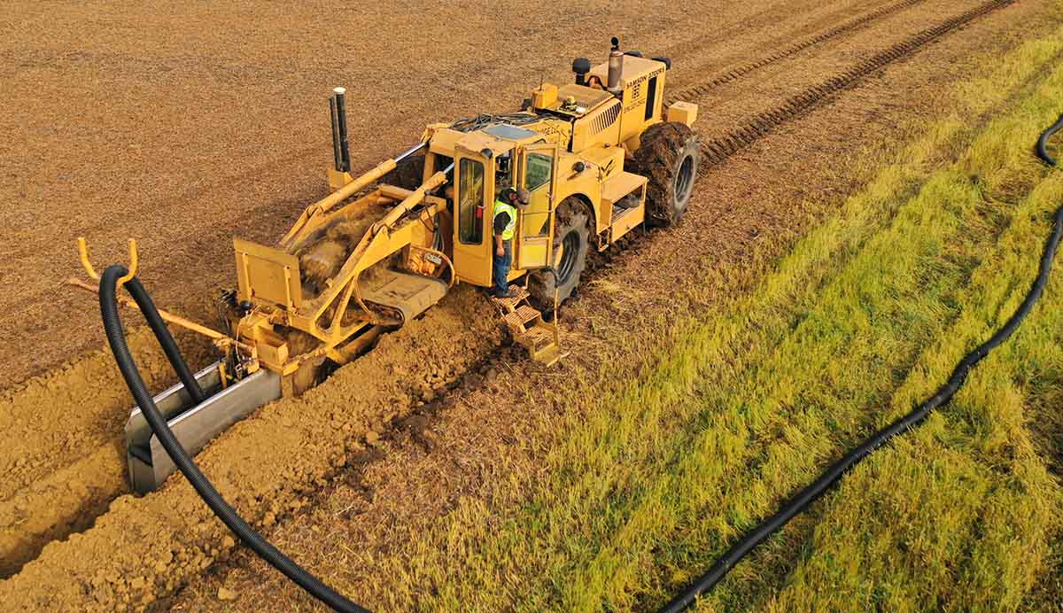 Machine installing black field tile in Iowa
