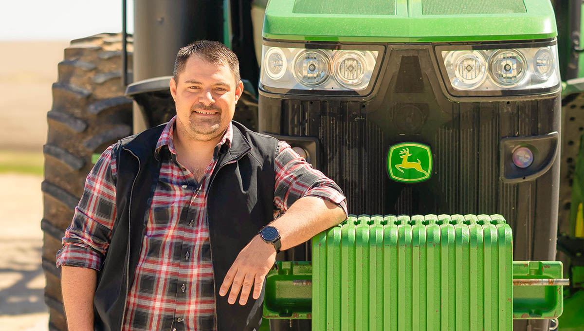 District 6 farmer-director leaning against John Deere t