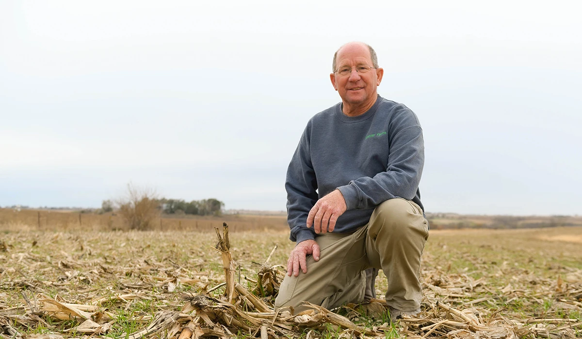Iowa farmer kneeling in corn stubble