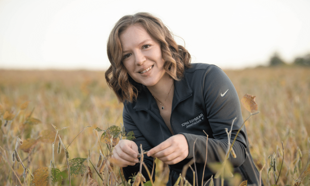 Teresa Middleton examines a soybean pod in a field duri