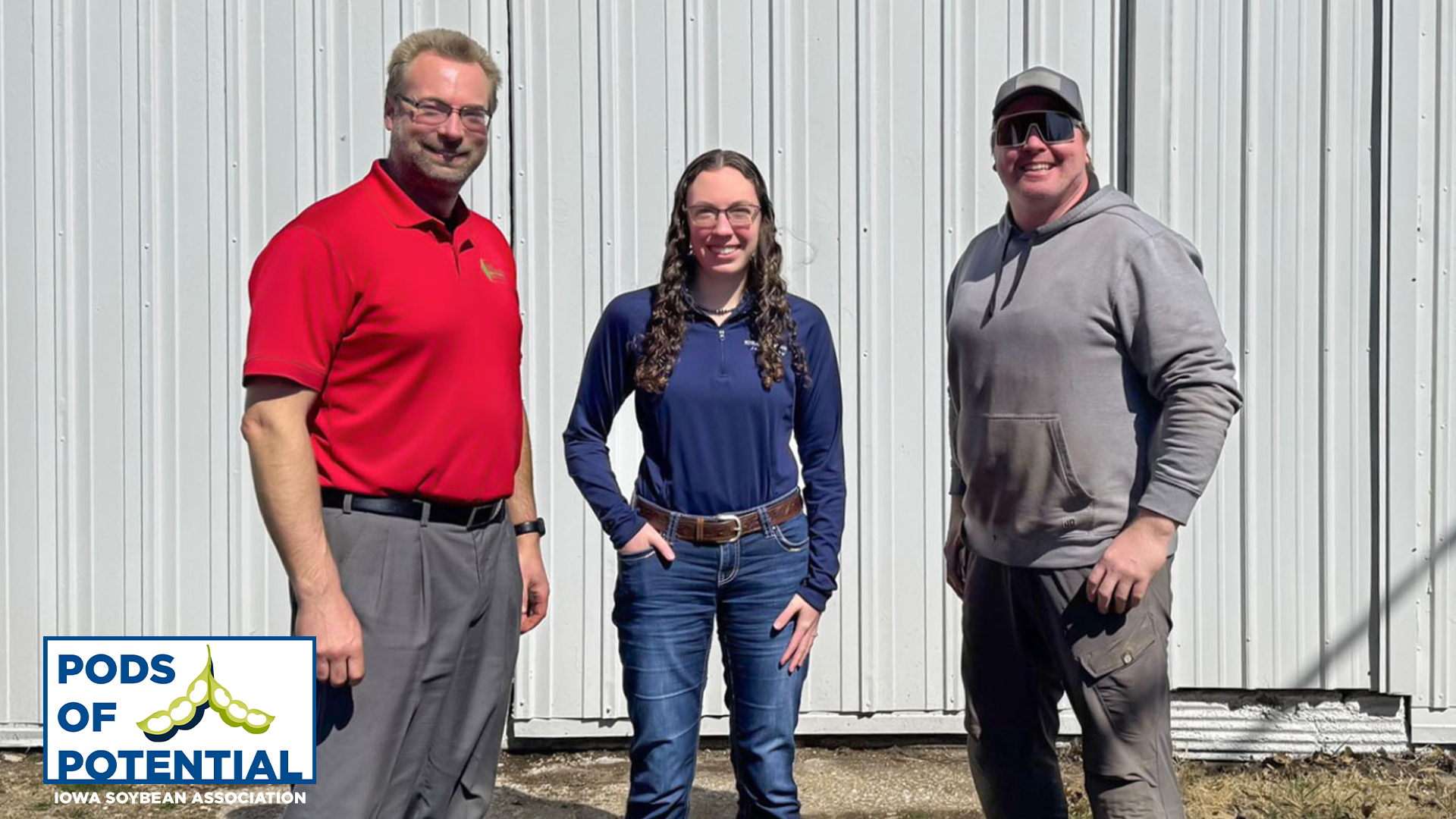 Three Farmers Stand in Front of a Shed