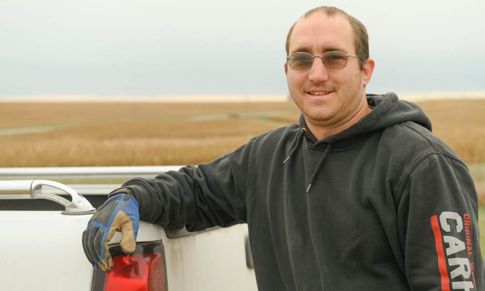 Chris Gaesser leans on his truck in a soybean field.