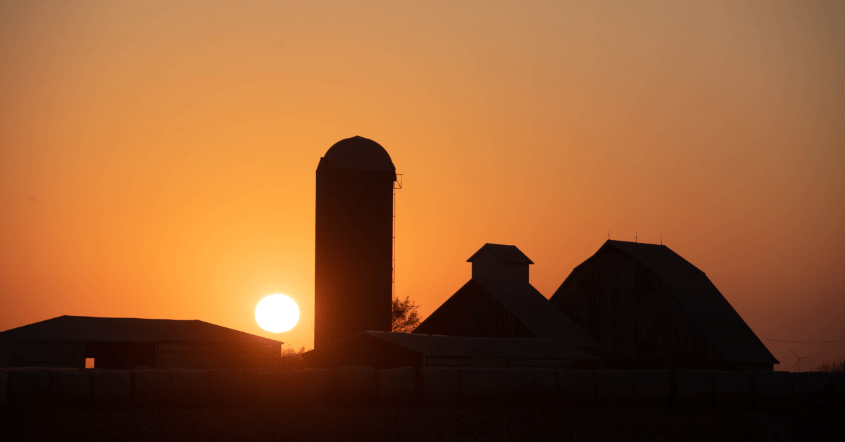 Sun sets orange over an Iowa farmstead.