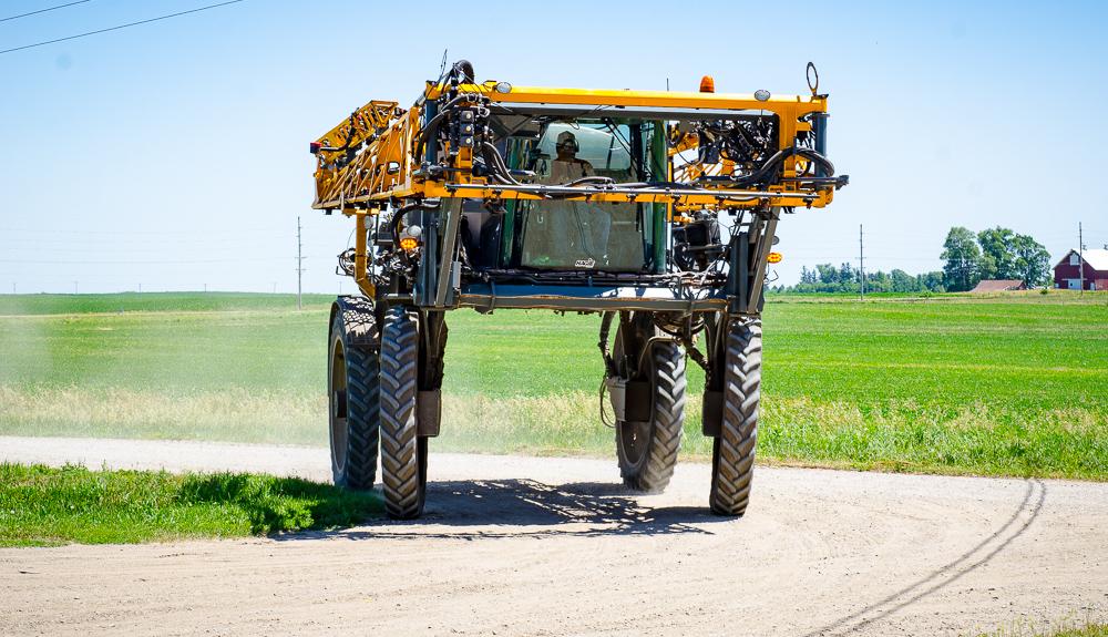 A Hagie sprayer pulls into a farmstead after applying h