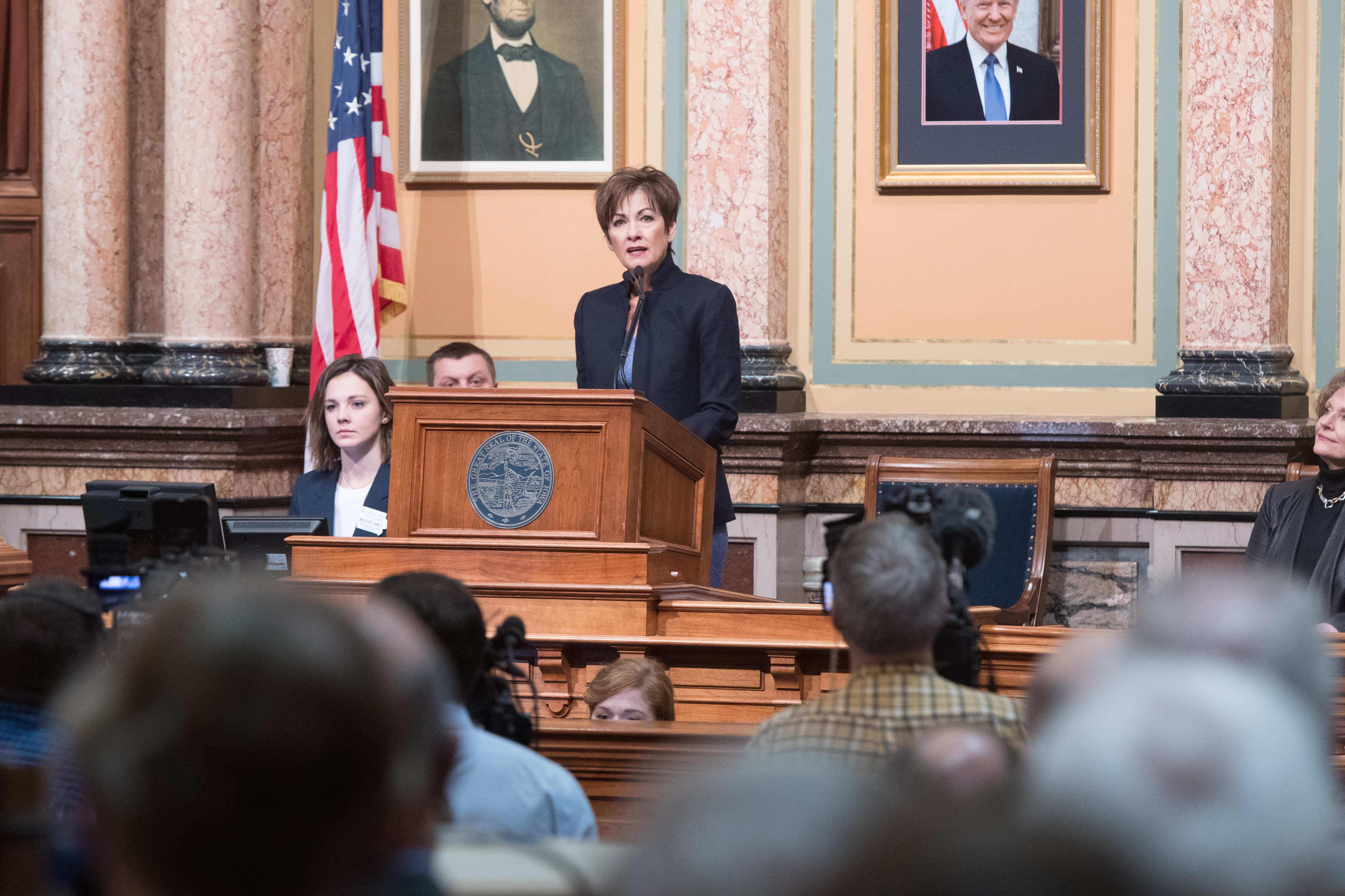 Governor Kim Reynolds speaks at a podium inside the Sta