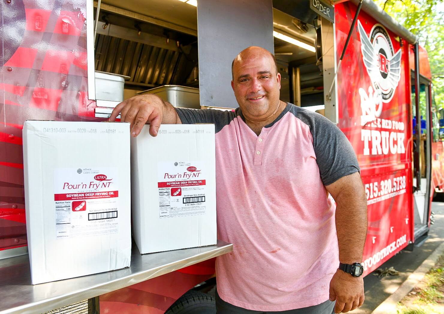 Shon Bruellman stands next to his food truck posing wit