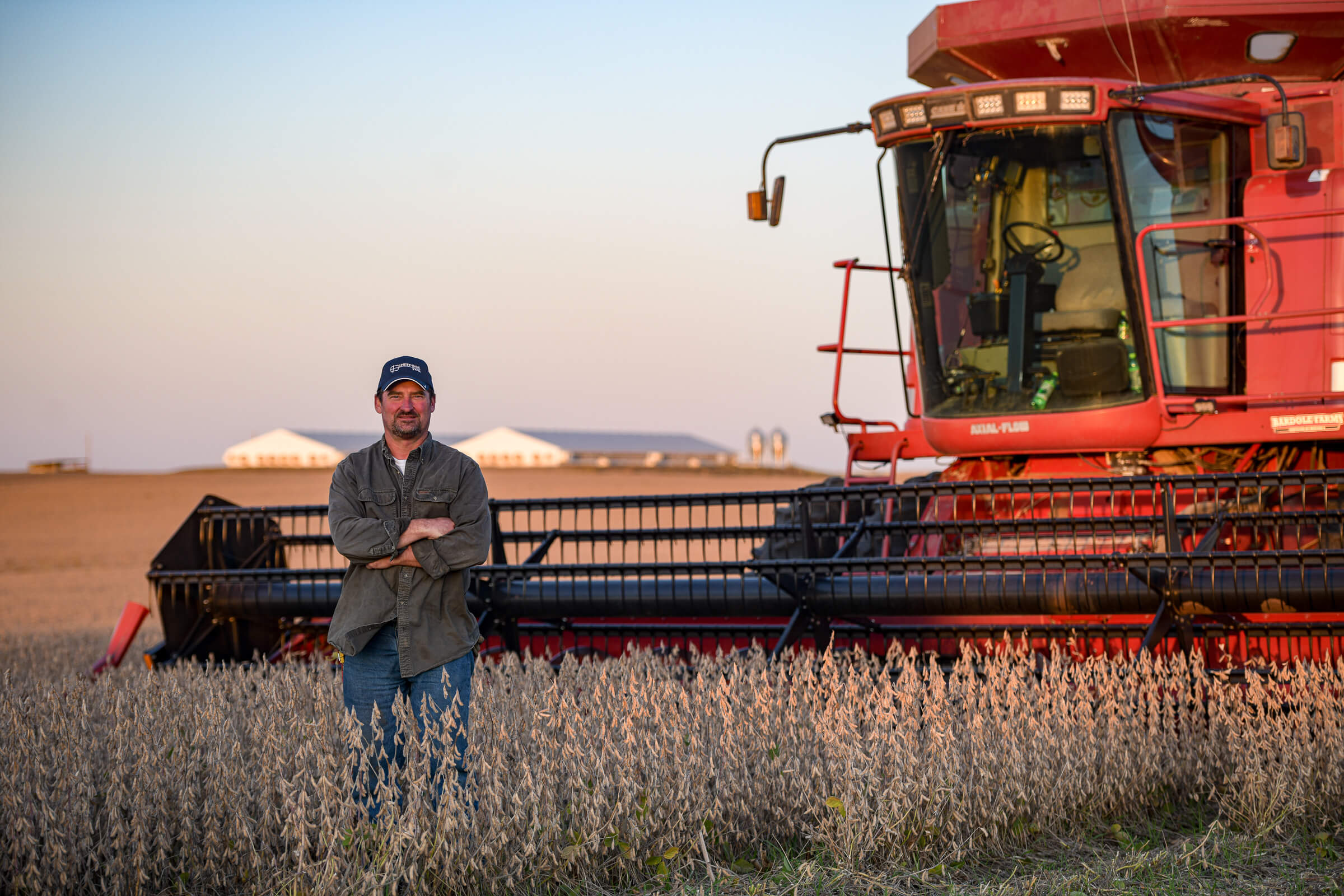 Tim Bardole standing in front of red combine during soy