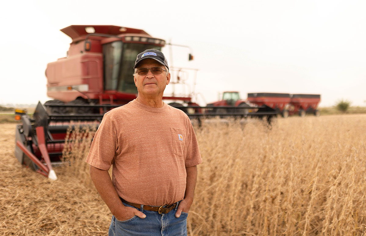 Farmer stands in field next to Case IH combine