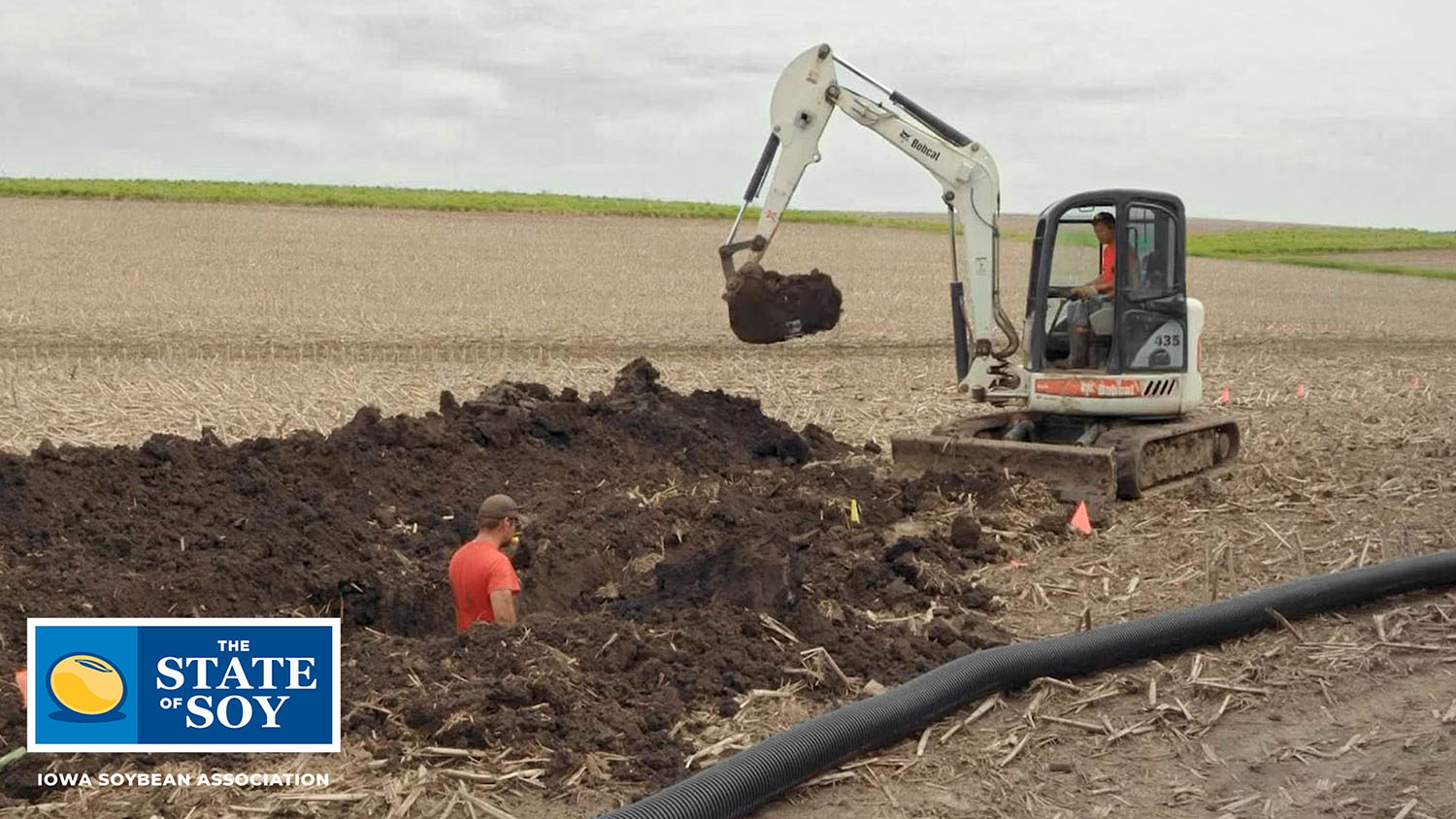 Backhoe digging trench for field tile