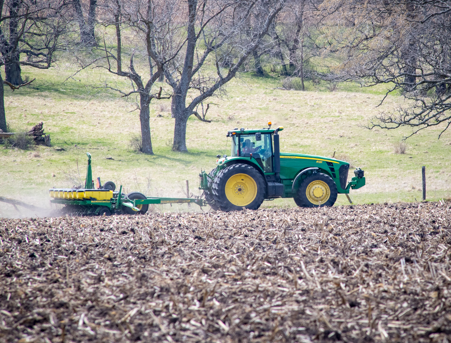 A tractor pulls a planter across the field