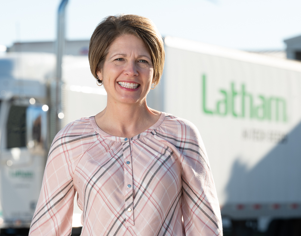 Shannon Latham stands in a pink plaid shirt in front of