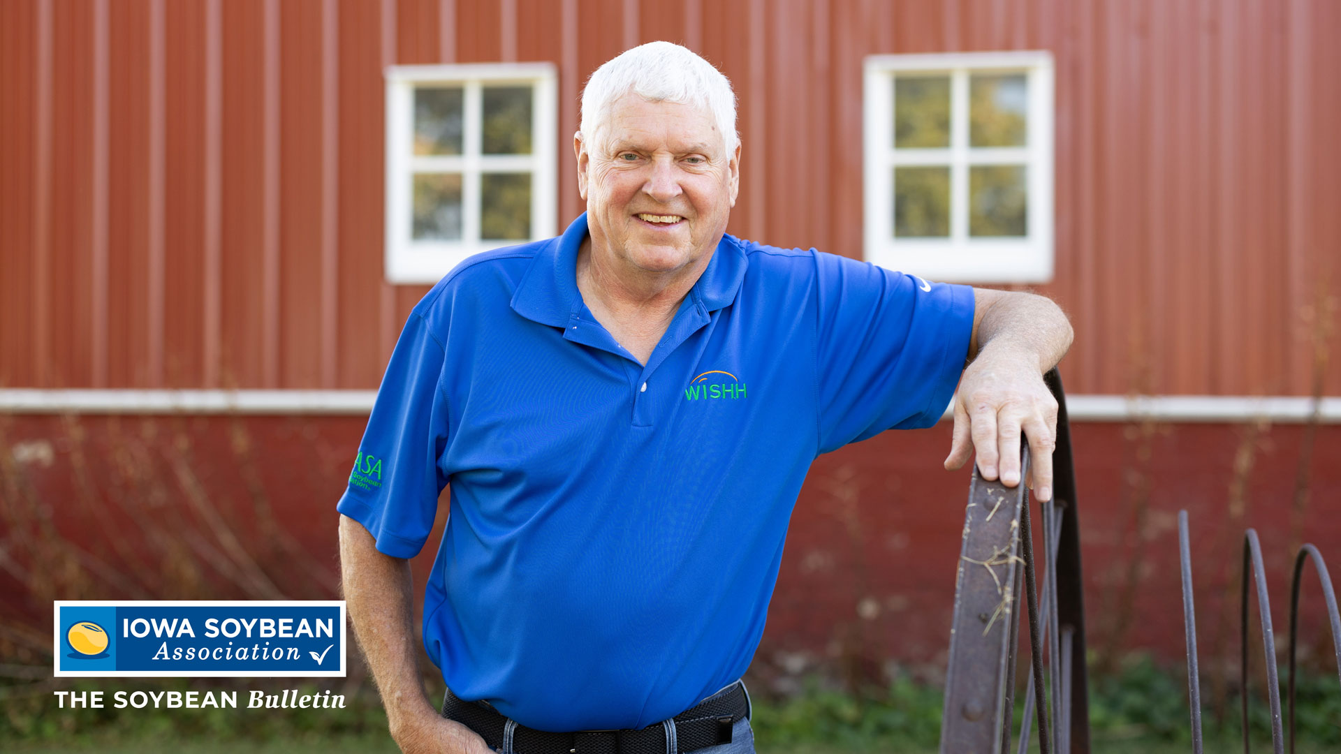 Farmer Leans on Fence in Front of Red Barn